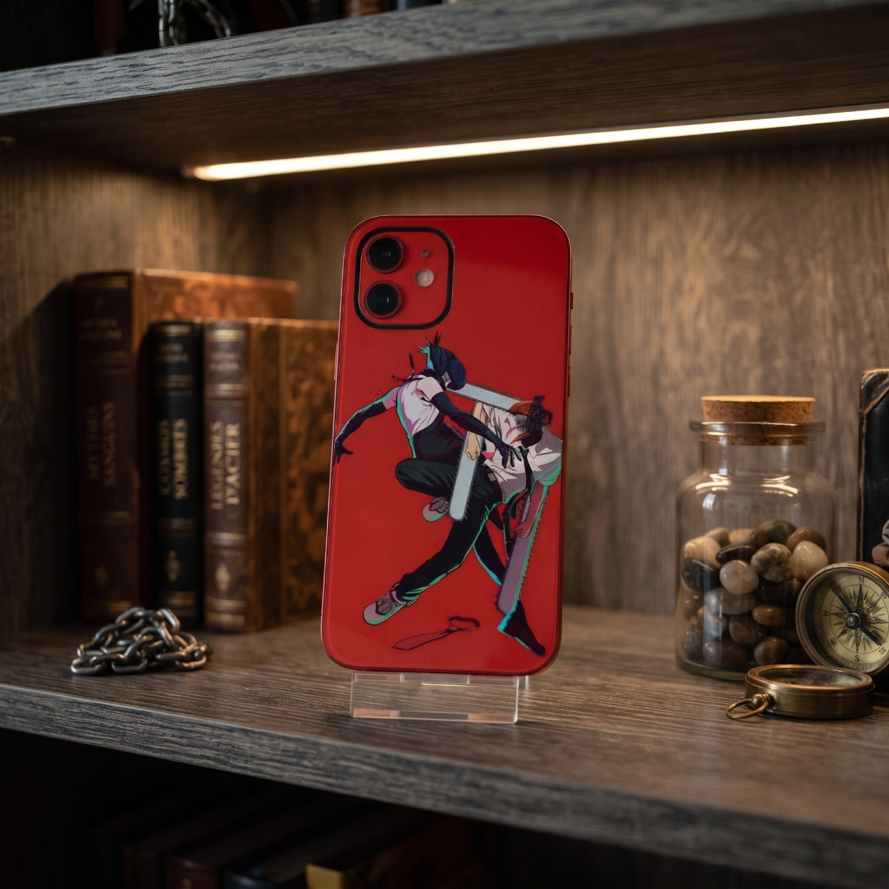 Coque iPhone Chainsaw Man Reze contre Denji posée sur une étagère en bois éclairée