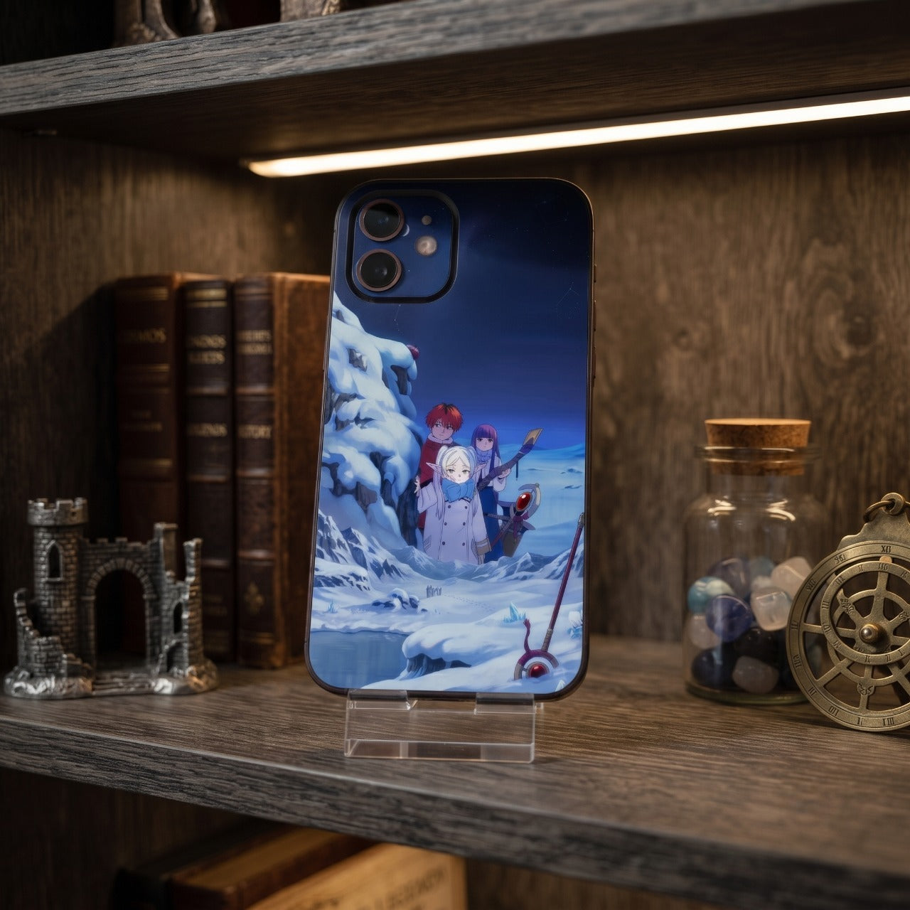 Coque iPhone Frieren sur un support, étagère en bois avec livres anciens, ruine de château miniature et bocal de pierres
