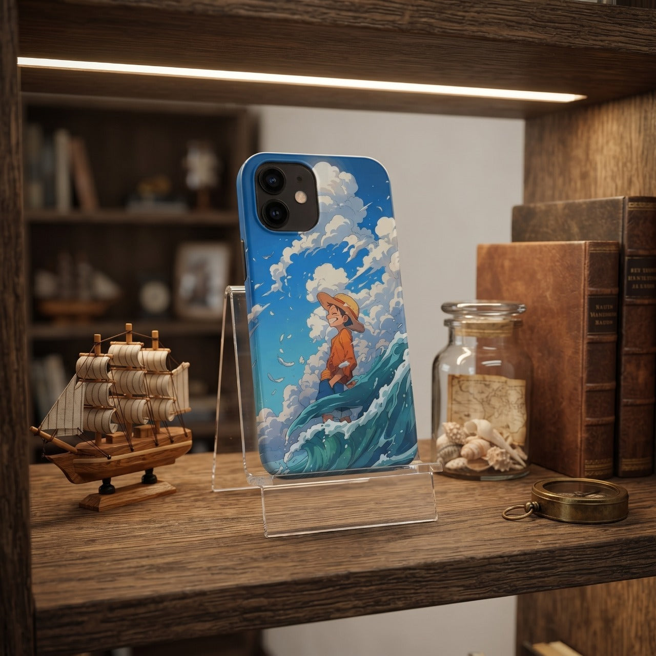 Coque iPhone One Piece jeune Luffy East Blue devant un voilier miniature et un bocal de coquillages