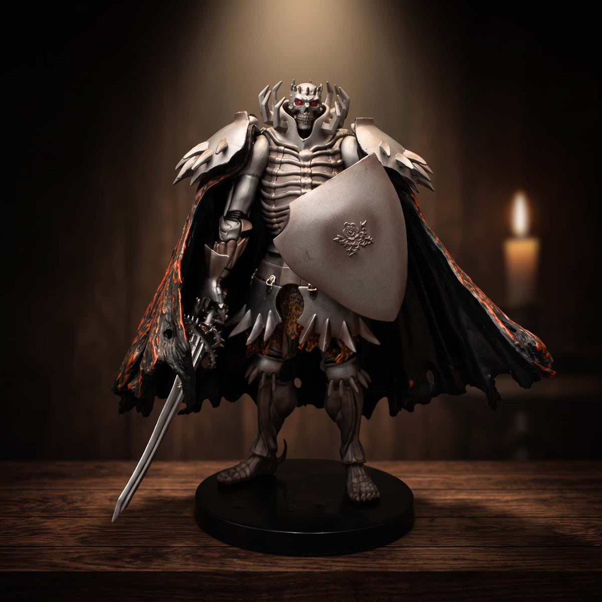 Figurine du Chevalier Squelette de Berserk, 21 cm, armure d'os, bouclier gravé d'une rose et cape noire doublée d'orange, sur une table en bois éclairée par une bougie