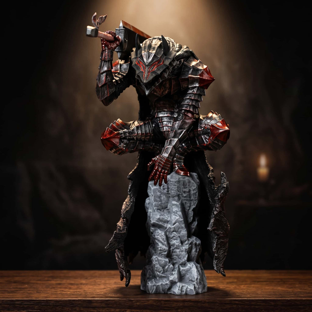Figurine de Guts en Armure du Berserker usée, perché au sommet d'une colonne de roche, épée Dragonslayer brandie au-dessus de lui, sur une table en bois dans une lumière de bougie