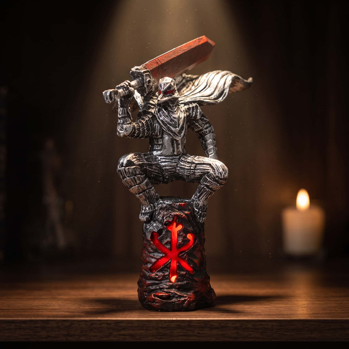 Figurine Berserk de 16 cm : Guts accroupi au sommet d'une colonne de roche, épée levée à deux mains, la Marque du Sacrifice gravée en rouge dans la pierre, sur une table en bois