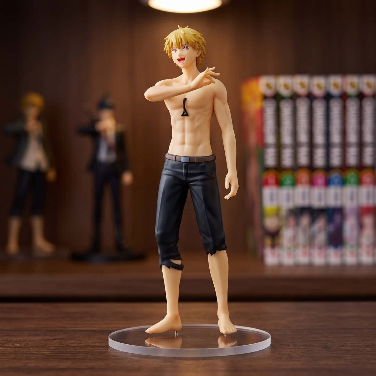 Figurine Chainsaw Man Denji 18 cm torse nu sur socle transparent, exposée sur une étagère devant des mangas (décor non inclus)