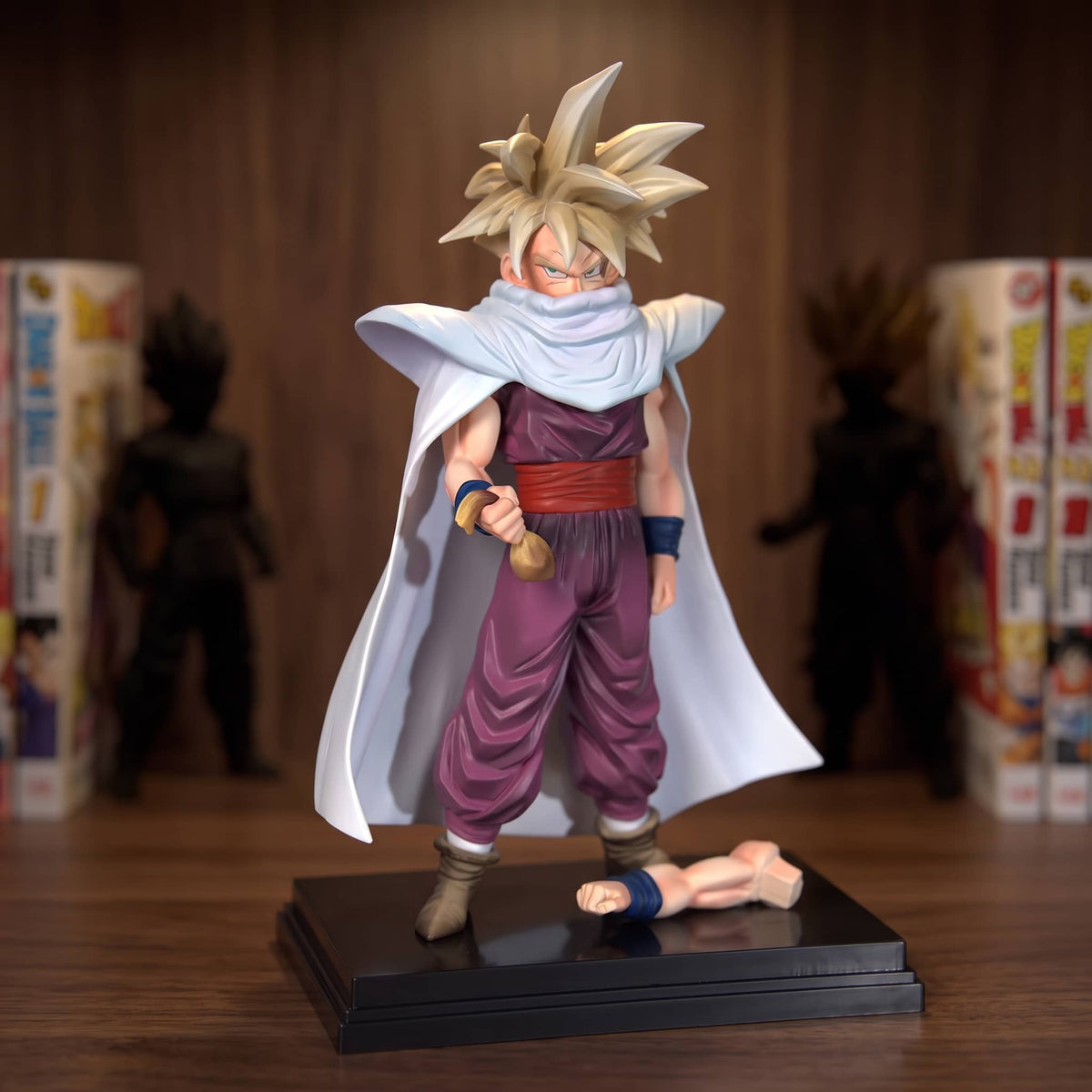Figurine Son Gohan adolescent (Dragon Ball), cape blanche moulée d'un bloc, en larges plis verticaux — posée sur une étagère en bois.