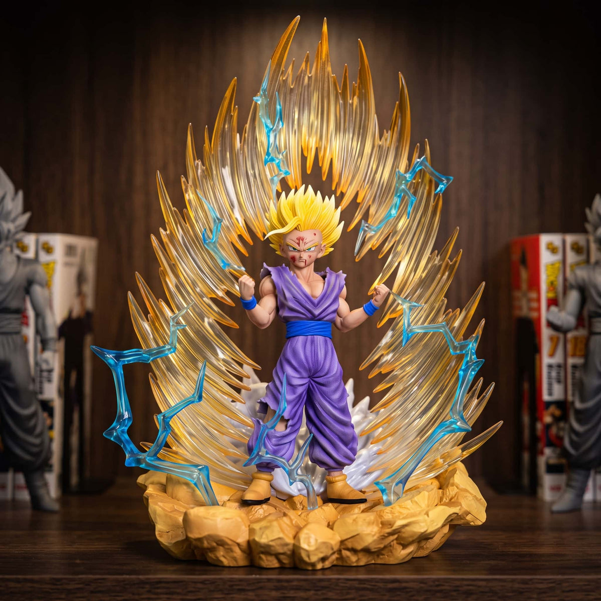 Figurine de Son Gohan Super Saiyan 2 en gi violet devant un mur d'aura dorée traversé d'éclairs bleus, 35 cm sur socle de rochers ocre, posée sur une étagère en bois