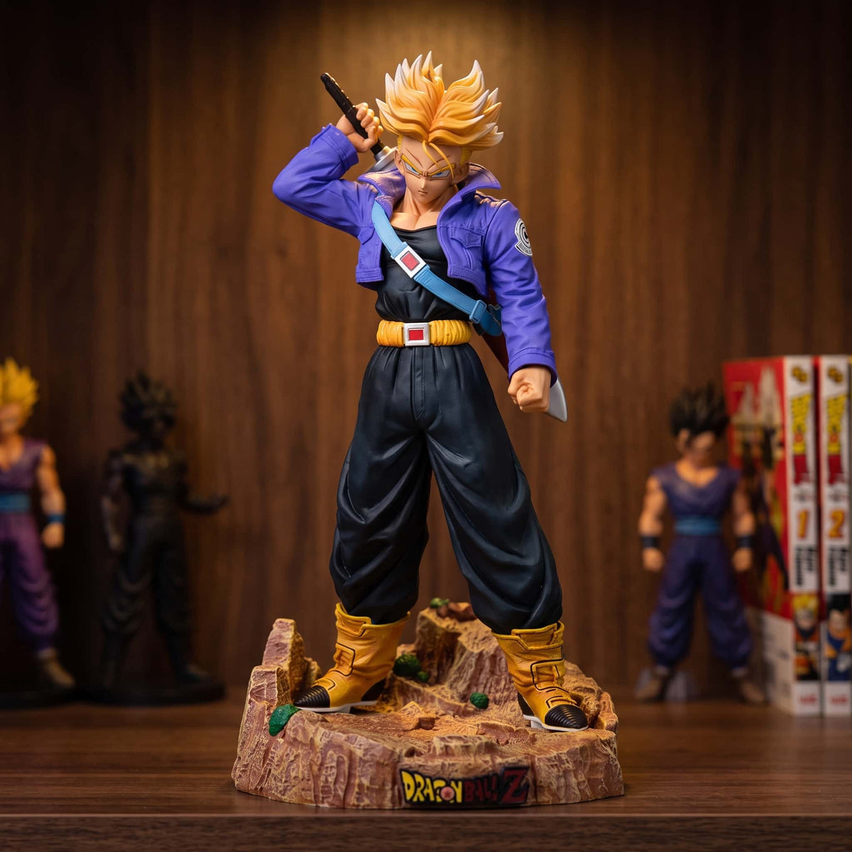 Figurine de Trunks du Futur en Super Saiyan de 23 cm, dégainant son épée, blouson violet et bandoulière bleue, sur un socle de terre craquelée posé sur une étagère en bois