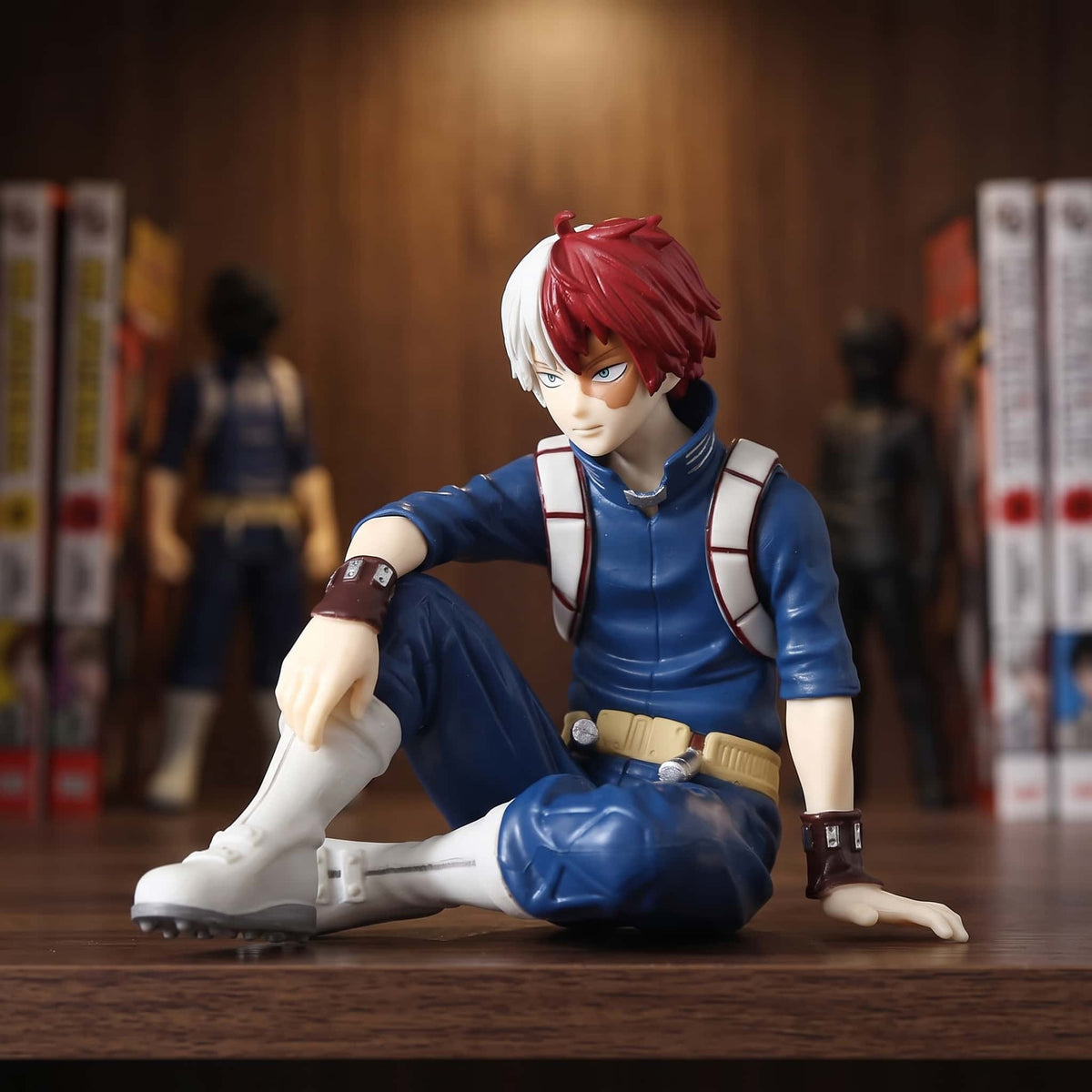 Figurine de Shoto Todoroki assis au sol en survêtement bleu de Yuei, cheveux mi-blancs mi-rouges et cicatrice à l'œil gauche, 10 cm, posée sur une étagère en bois