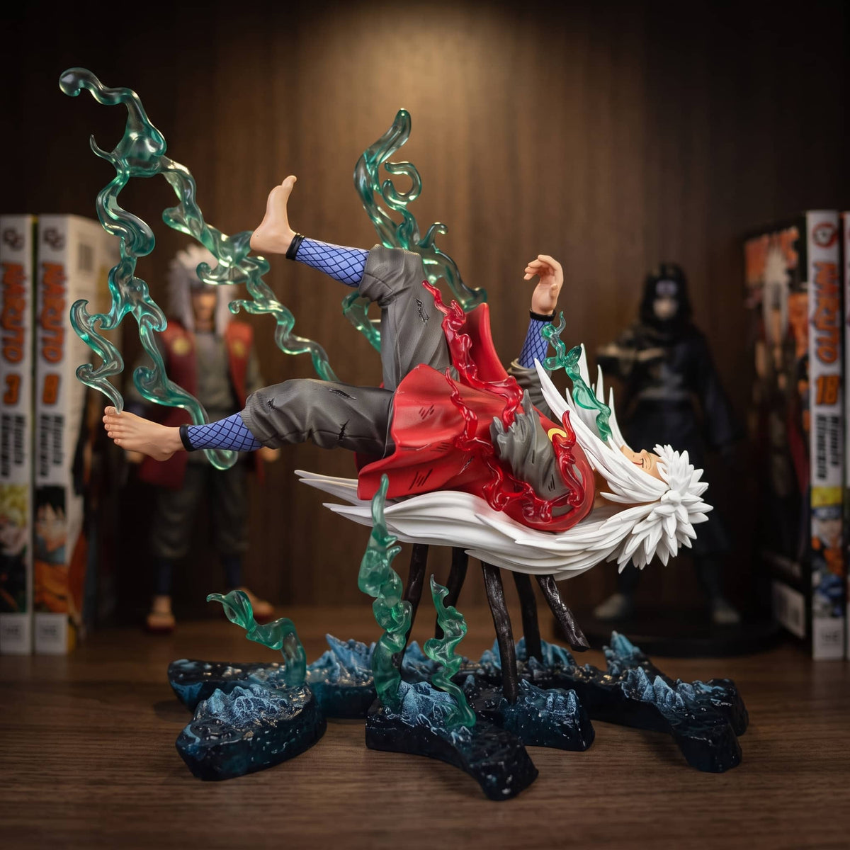 Figurine Jiraiya (Naruto), un diorama : volutes translucides et blocs de roche — posée sur une étagère en bois.