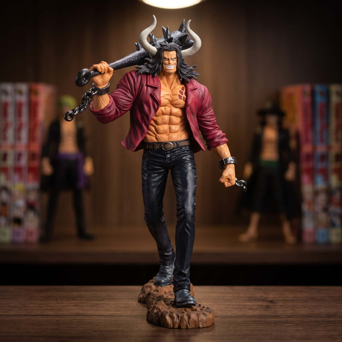 Figurine One Piece Kaido jeune 19 cm, massue sur l'épaule, exposée sur une étagère devant des mangas (décor non inclus)