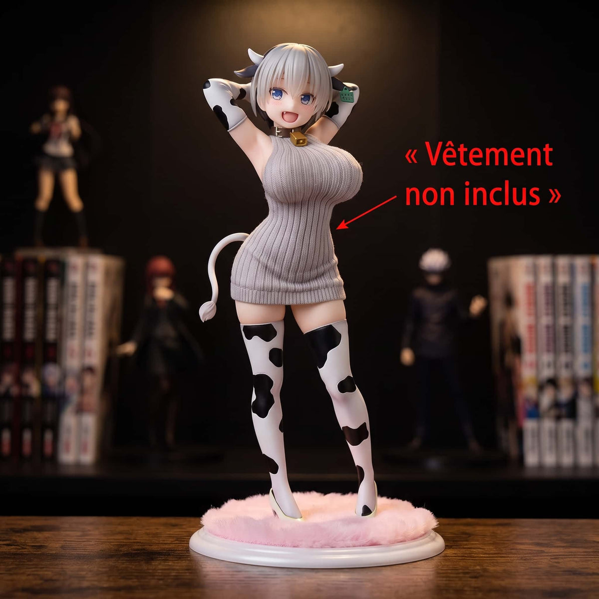 Figurine Hana Uzaki 23 cm d'Uzaki-chan, cornes de vache, clochette dorée et bas tachetés, sur son socle rose duveteux, présentée avec un pull gris non inclus devant une étagère (décor non inclus)
