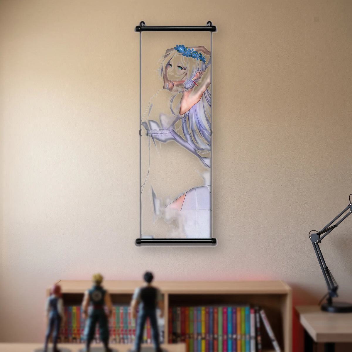 Kakémono Frieren, Frieren en robe blanche, une couronne de fleurs bleues sur la tête, bras levés, suspendu au mur beige d'une chambre au-dessus d'une étagère de tomes de manga