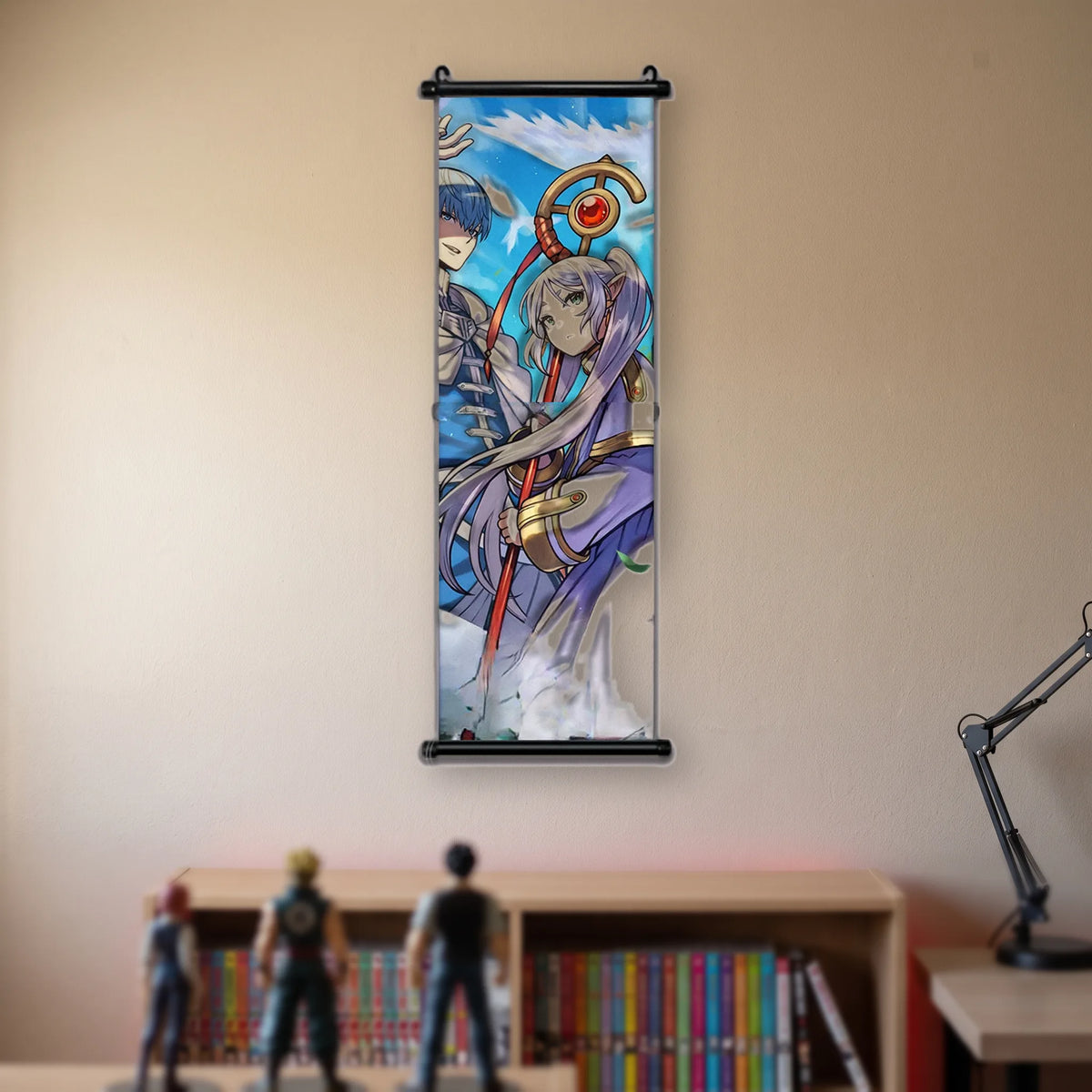 Kakémono Frieren, Frieren au bâton, et Himmel derrière elle, sous un ciel traversé d'oiseaux, suspendu au mur beige d'une chambre au-dessus d'une étagère de tomes de manga