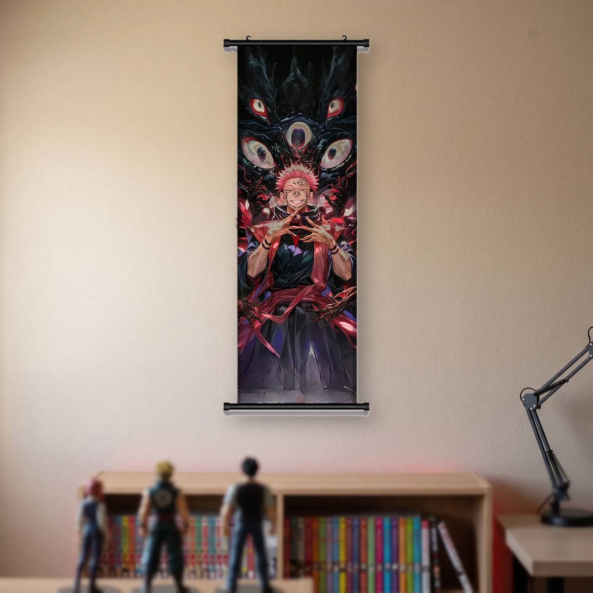 Kakémono Jujutsu Kaisen Sukuna les mains jointes devant quatre grands yeux blancs, suspendu au mur beige d'une chambre au-dessus d'une étagère de tomes de manga et de figurines