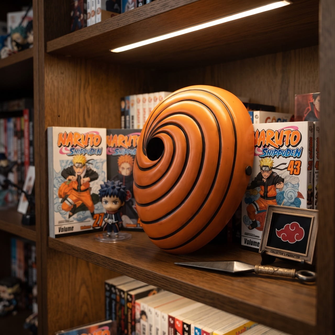 Masque orange en spirale de Tobi posé sur une étagère sombre, éclairé de côté