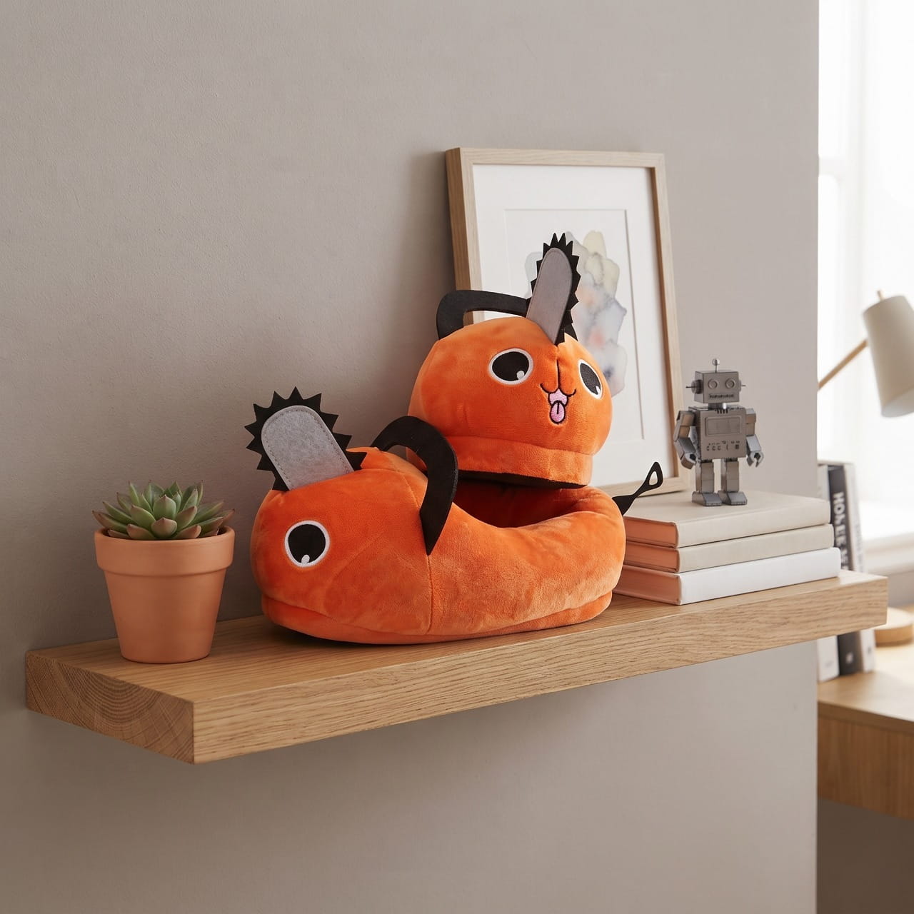 Chaussons Pochita en peluche orange posés au pied d'une étagère en bois