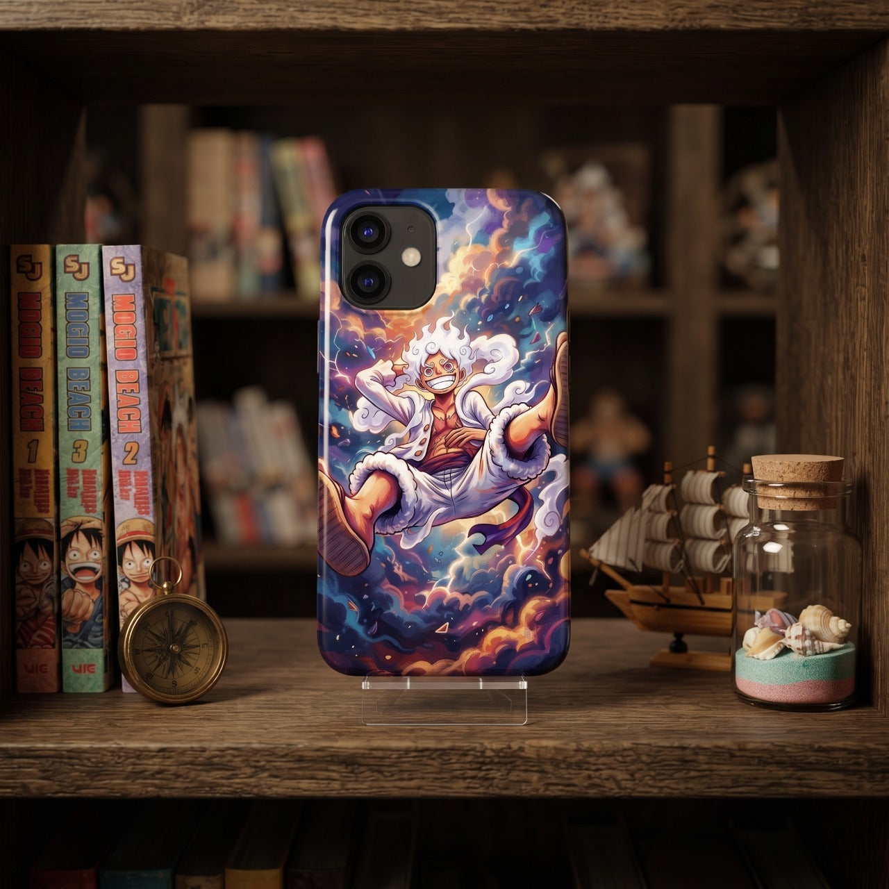 Coque iPhone One Piece Luffy Gear 5 aux couleurs vives, devant une rangée de tomes manga et un voilier miniature