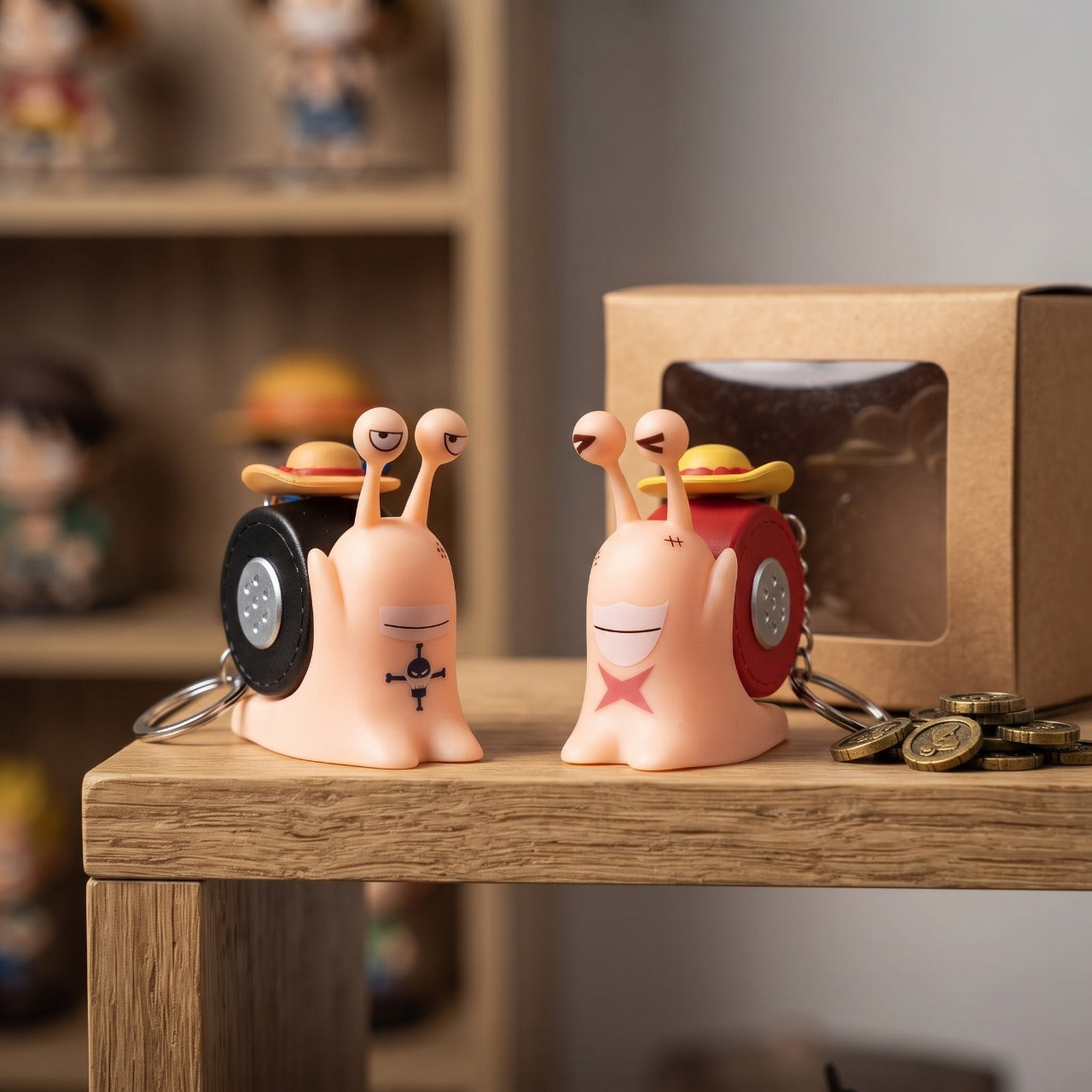 Deux Den Den Mushi One Piece porte-clés posés devant leur boîte sur une étagère