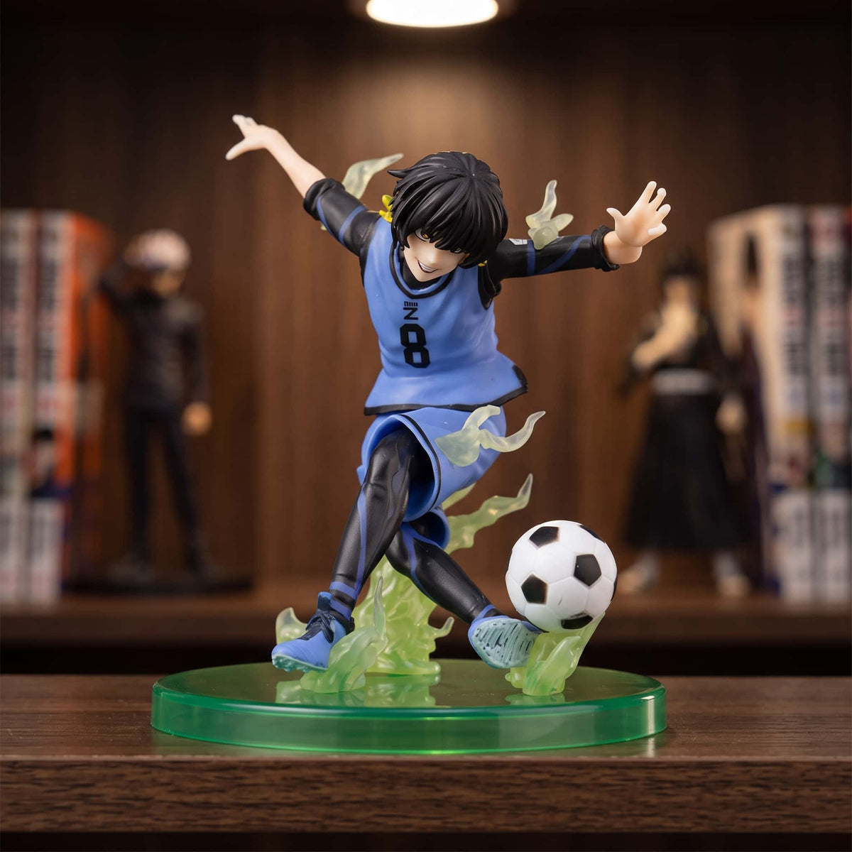 Figurine Bachira Meguru (Blue Lock), 12 cm, saisi au moment de la frappe — posée sur une étagère en bois.