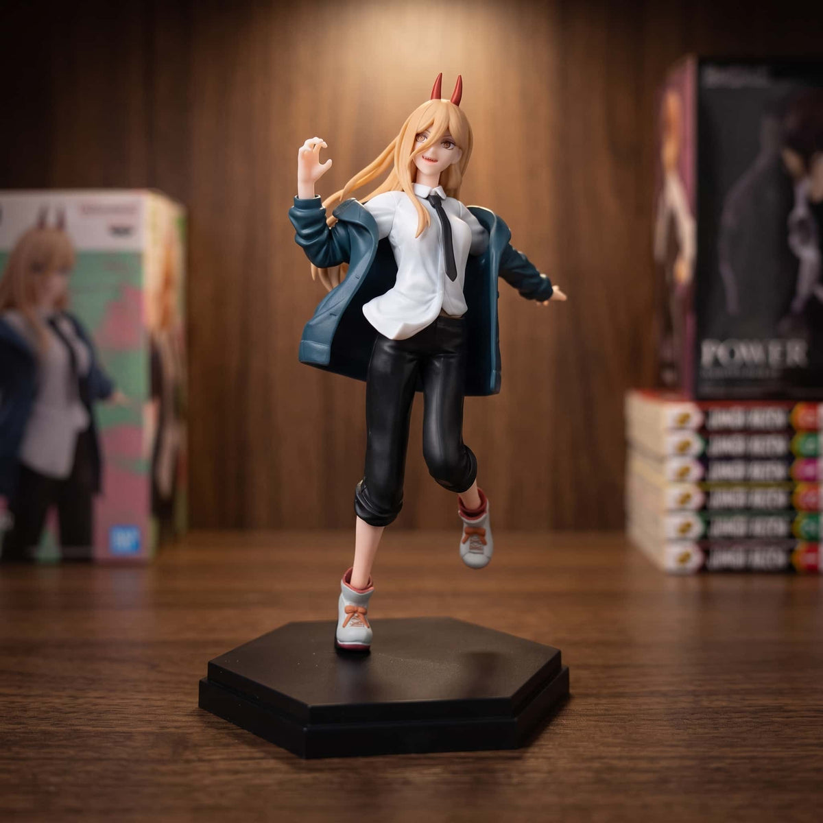 Figurine de Power de Chainsaw Man en pleine course : cornes rouges, cheveux blonds, chemise blanche et cravate, veste bleu canard tombée des épaules, 20 cm sur socle hexagonal noir, posée sur une étagère en bois