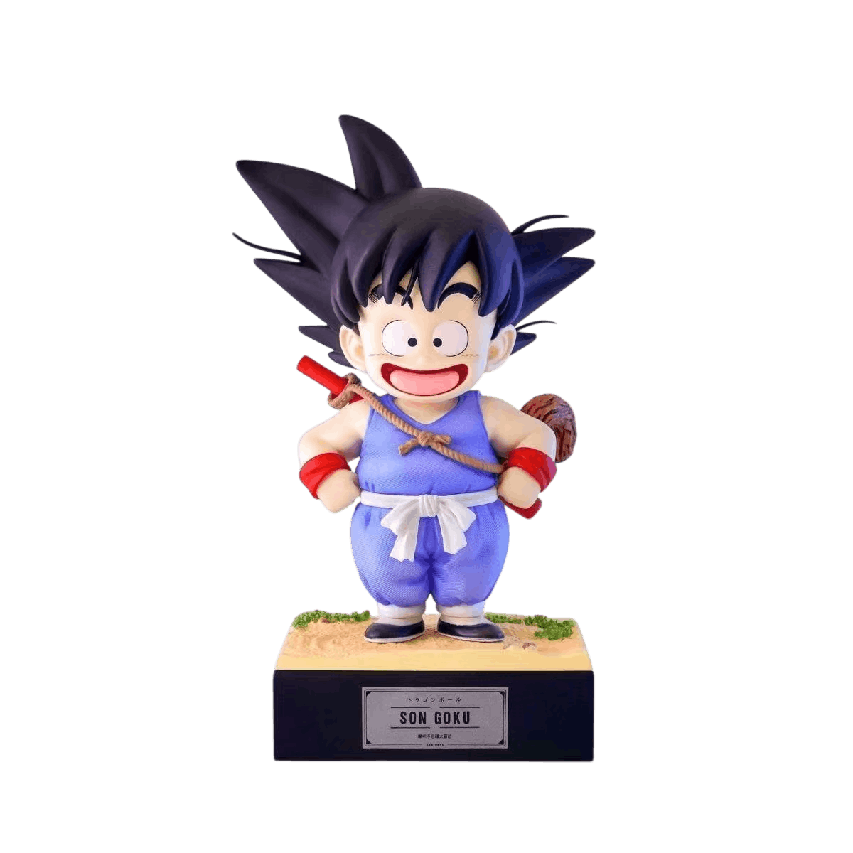 Figurine Goku enfant détourée sur fond noir, sourire ouvert, bâton magique en travers du dos et socle sableux