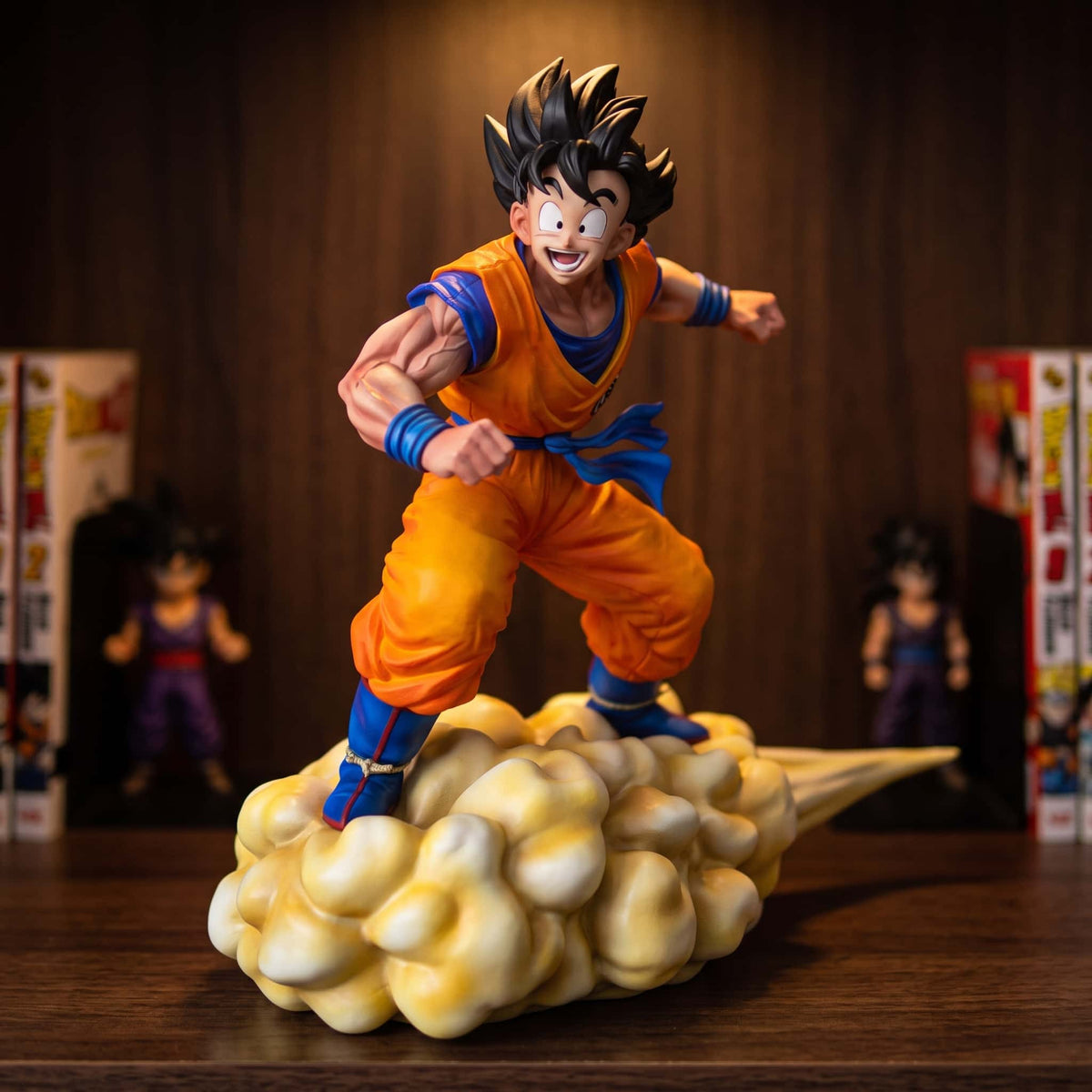 Figurine de Goku debout sur le Nuage Magique, buste penché en avant, 31 cm, gi orange et ceinture bleue, traînée jaune effilée, posée sur une étagère en bois sombre