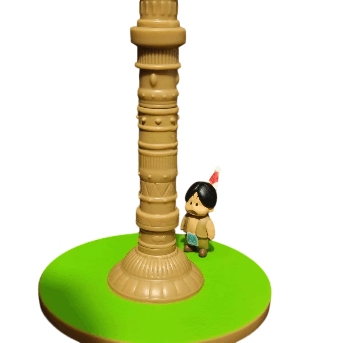 Gros plan sur Upa au pied de la Tour de Karin, plume dans les cheveux et socle d'herbe verte