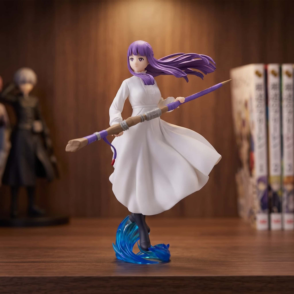 Figurine Frieren Fern 18 cm en robe blanche, bâton en main, exposée sur une étagère devant des mangas (décor non inclus)