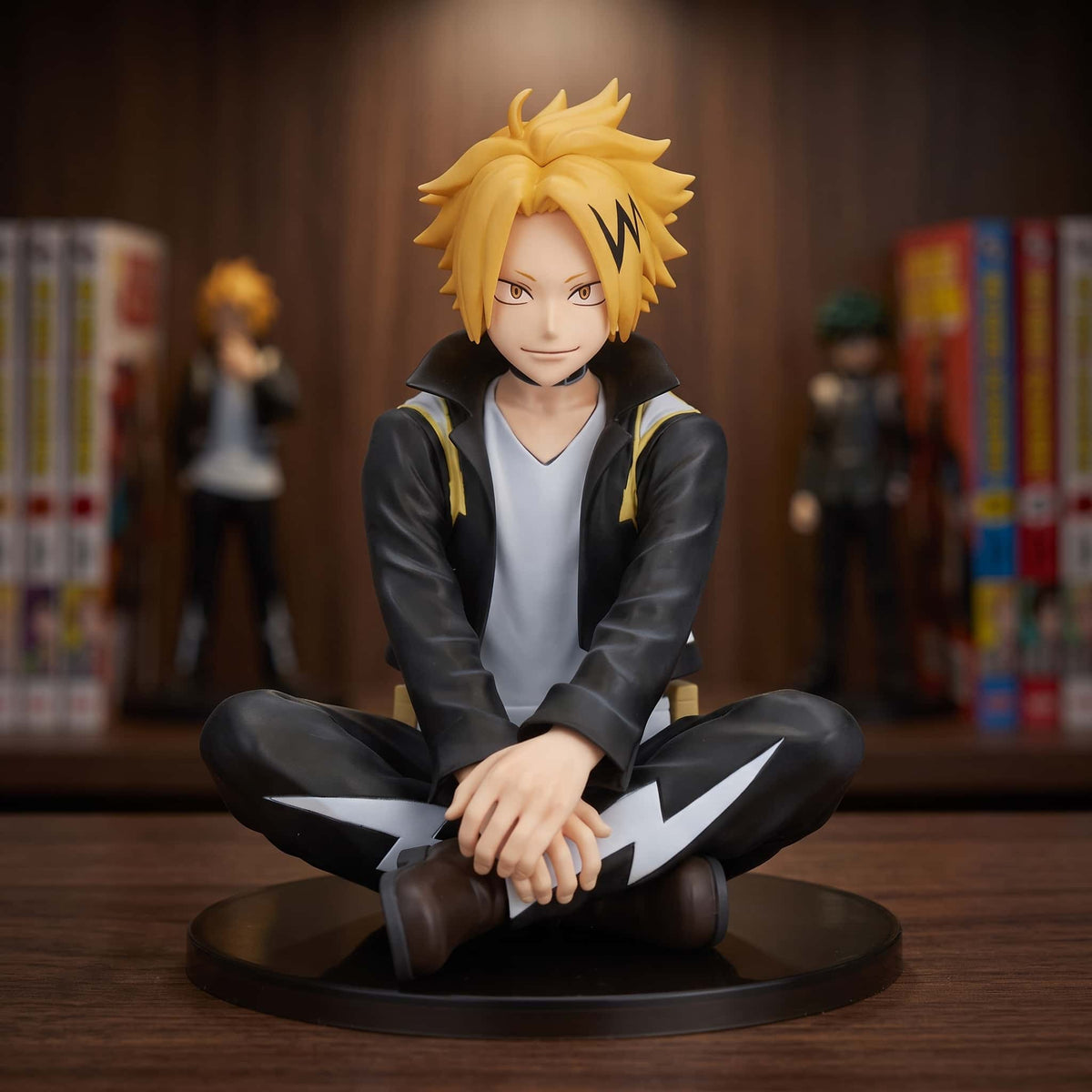 Figurine de Denki Kaminari assis en tailleur, blouson noir à éclairs jaunes et mèche noire en zigzag, 11 cm sur socle noir, posée sur une étagère en bois