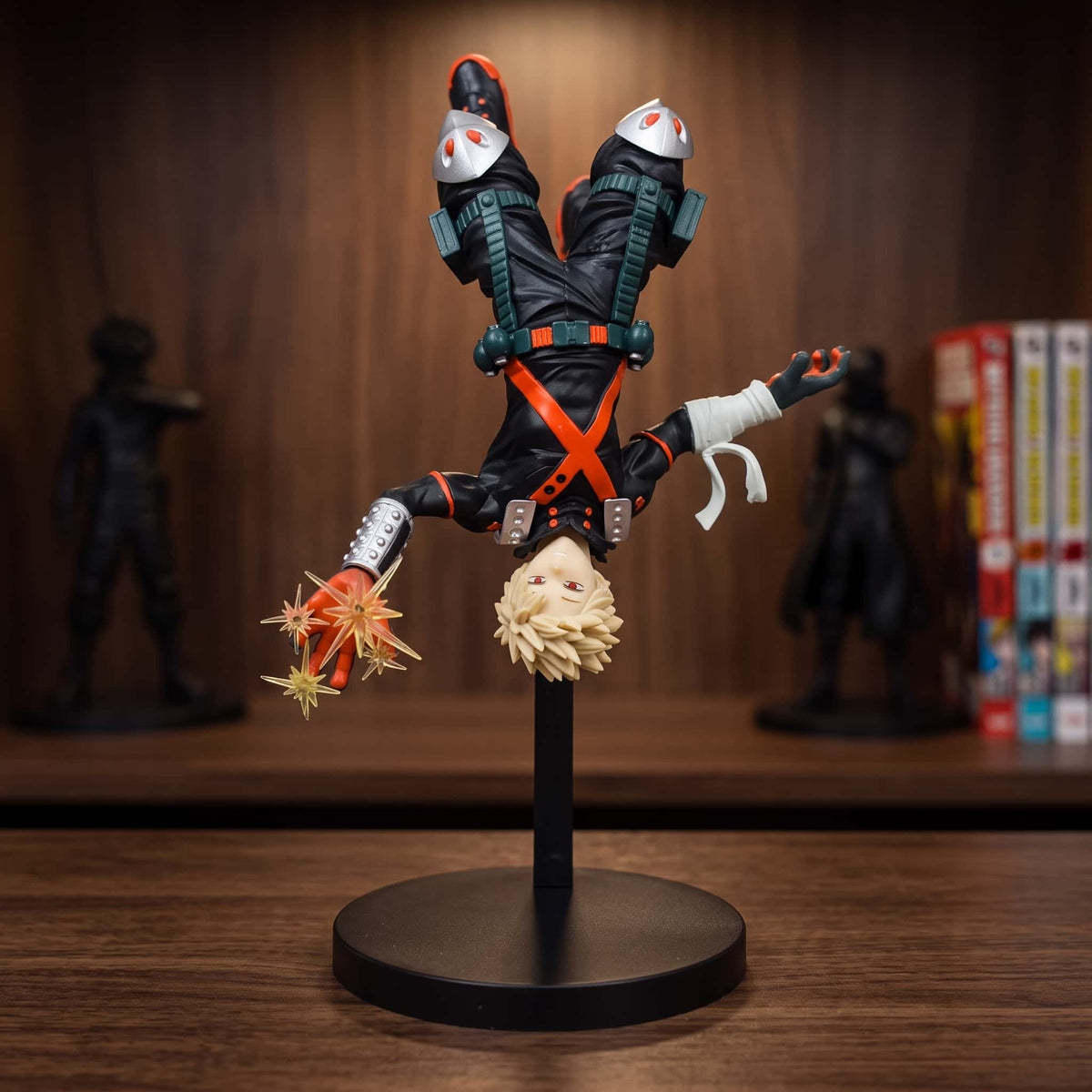 Figurine de Katsuki Bakugo en piqué tête en bas, explosion orange translucide à la main, montée sur un montant noir et un socle circulaire, 22 cm, posée sur une étagère en bois