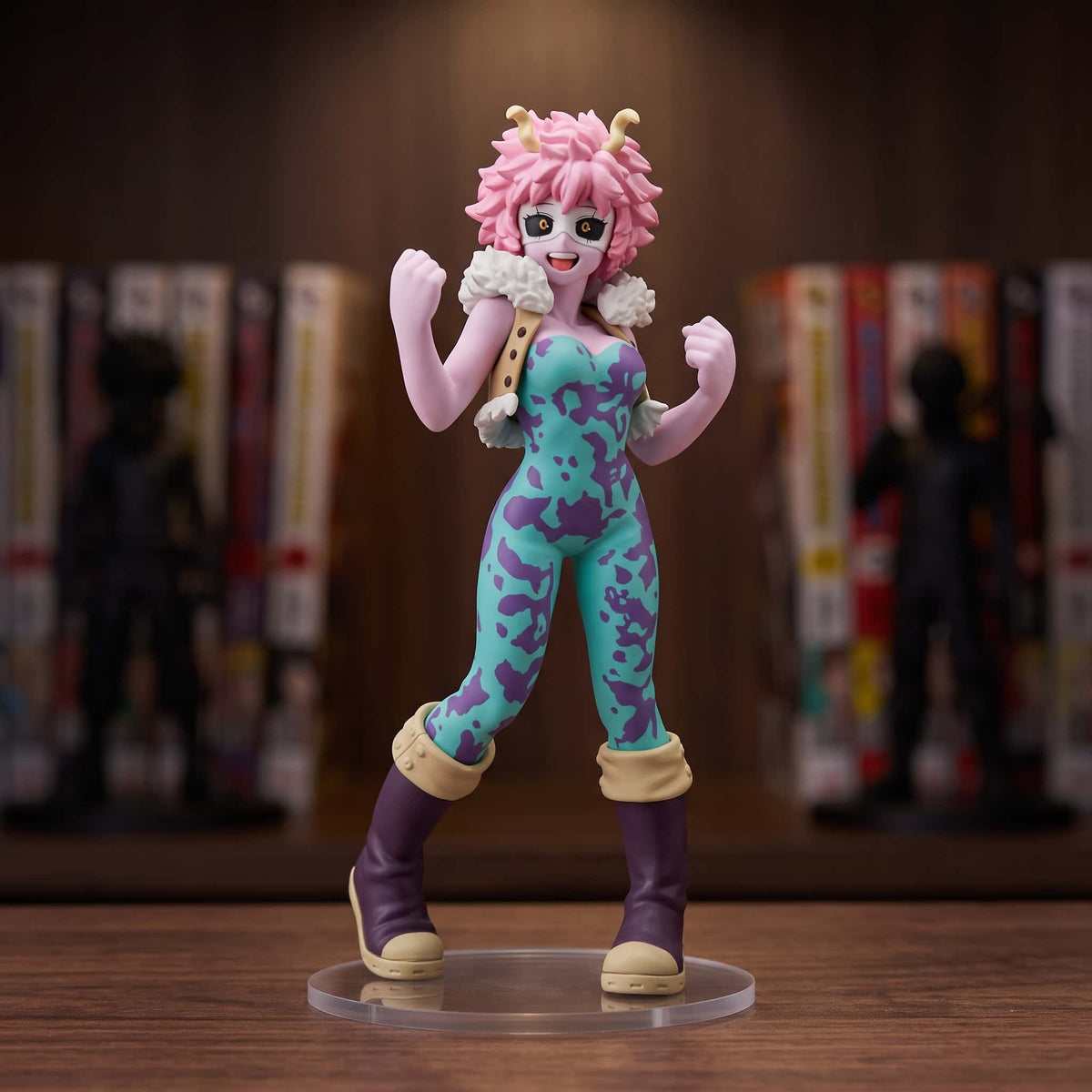 Figurine de Mina Ashido poings levés, peau rose, cornes jaunes et combinaison turquoise et violette, 16 cm sur socle transparent, posée sur une étagère en bois