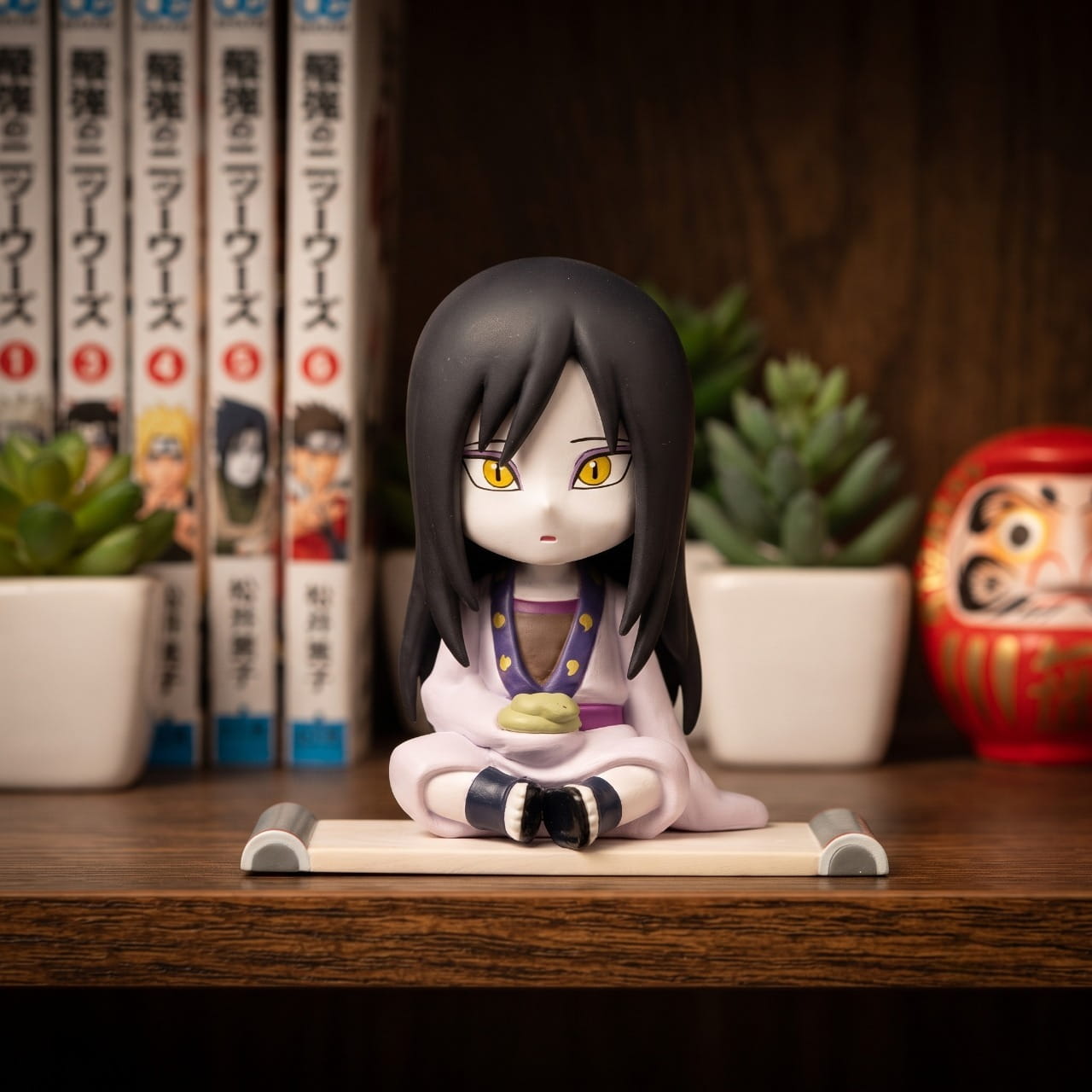 Figurine chibi Orochimaru — assis en kimono clair, yeux jaunes à pupille fendue — Naruto, étagère (décor non inclus)