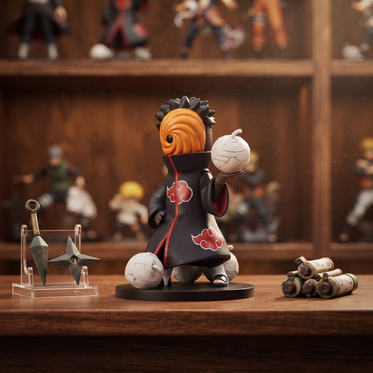 Figurine chibi Tobi au masque orange à spirale, posée sur une étagère en bois près d'un présentoir à kunai et de rouleaux de parchemin — Naruto (décor non inclus)