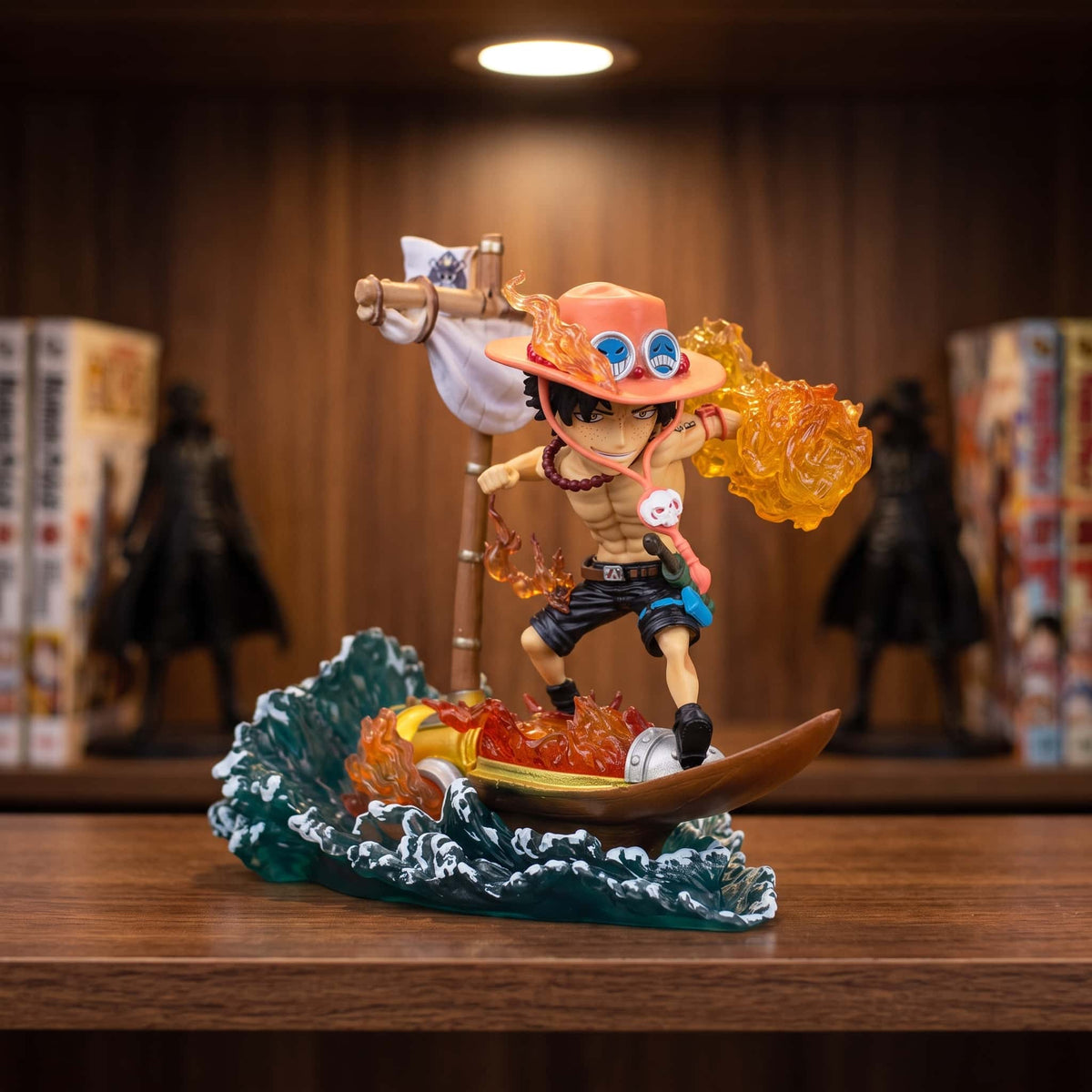 Figurine chibi One Piece Portgas D. Ace 11 cm sur son Striker au milieu des vagues, exposée sur une étagère devant des mangas (décor non inclus)