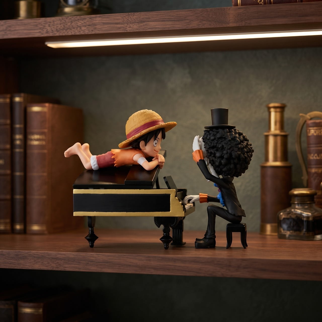 Diorama One Piece Brook au piano avec Luffy allongé sur le couvercle, exposé sur une étagère (décor non inclus)