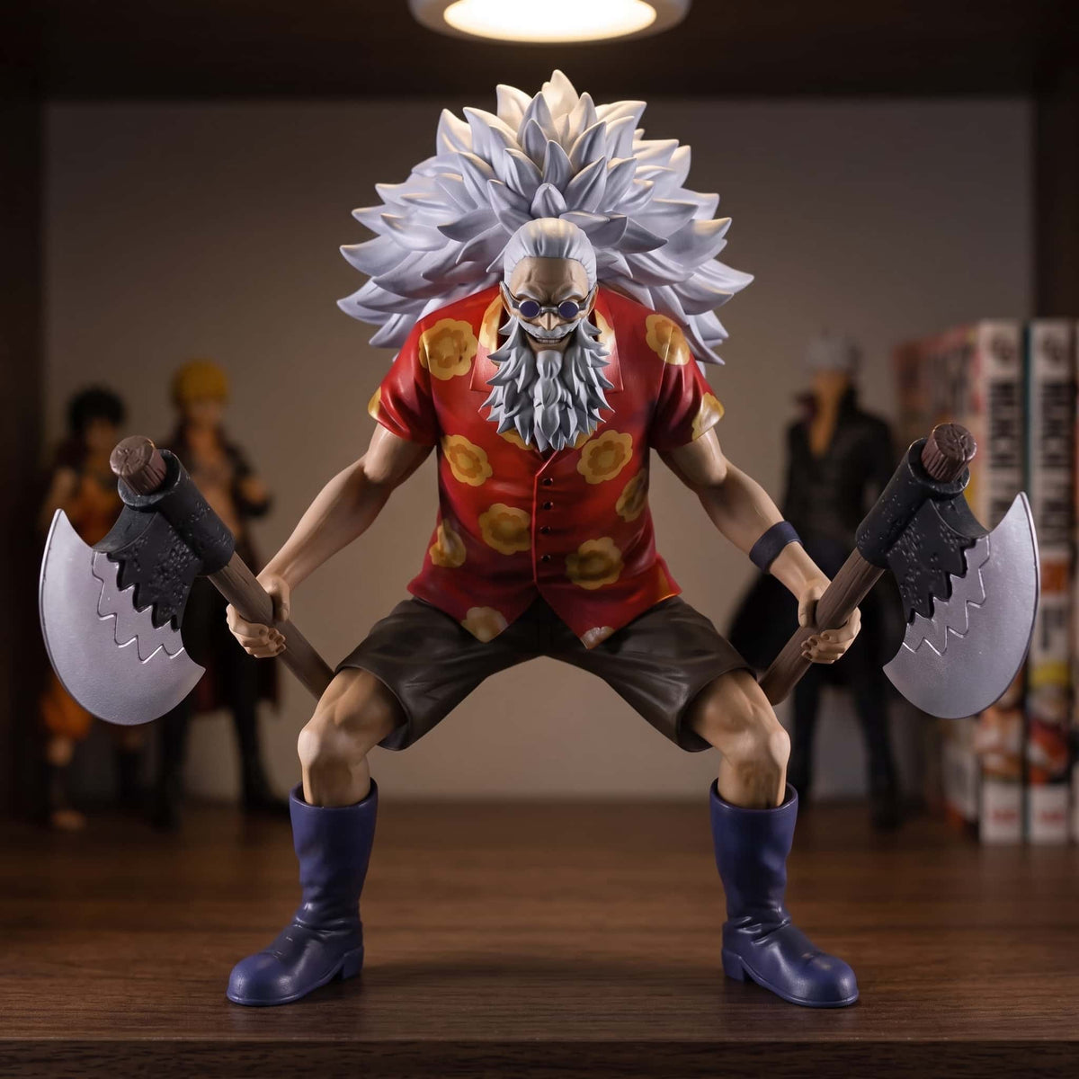 Figurine One Piece Scopper Gaban 16 cm en garde avec ses deux haches, exposée sur une étagère devant des mangas (décor non inclus)