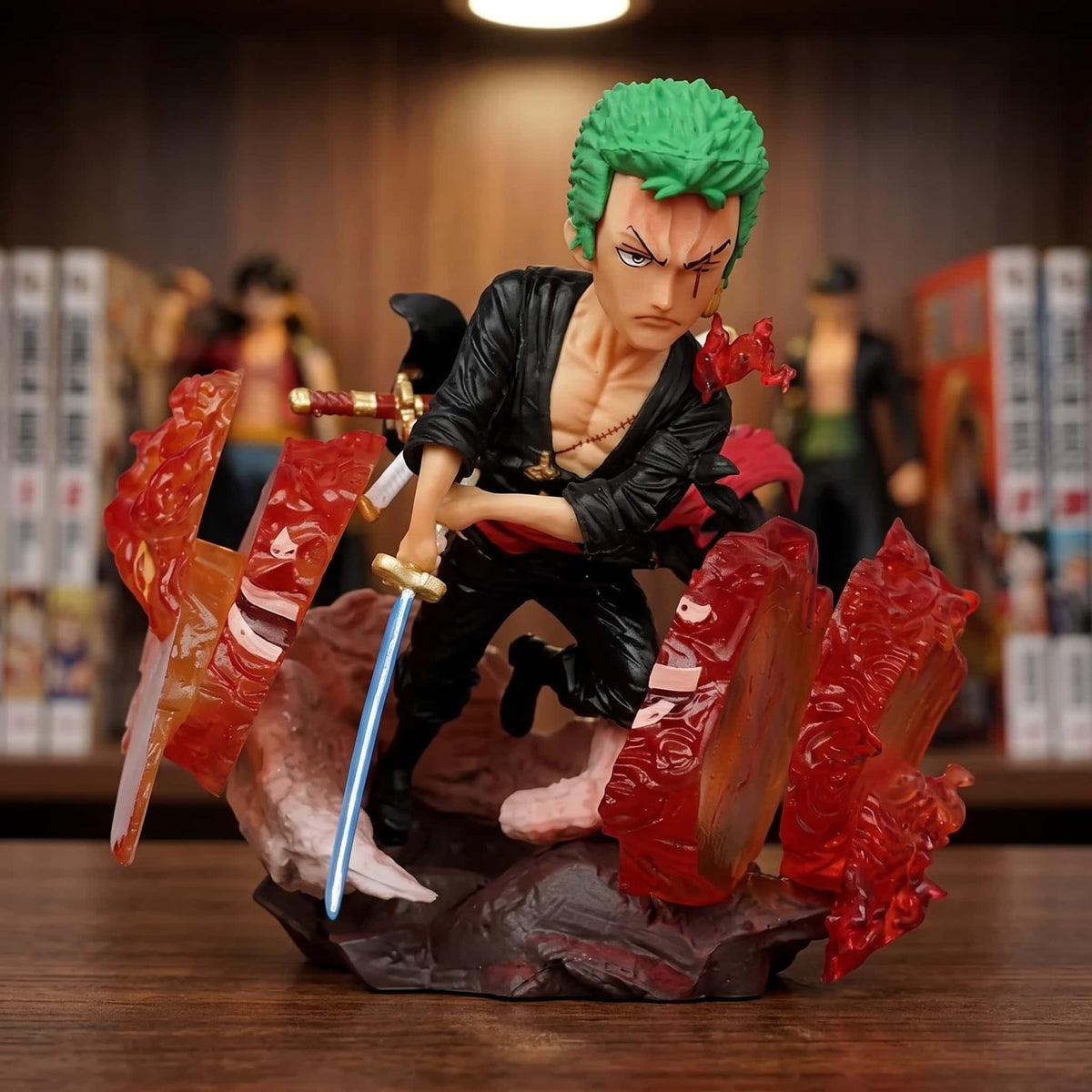 Figurine chibi One Piece Roronoa Zoro 9 cm lame au clair entre des éclats rouges, exposée sur une étagère devant des mangas (décor non inclus)