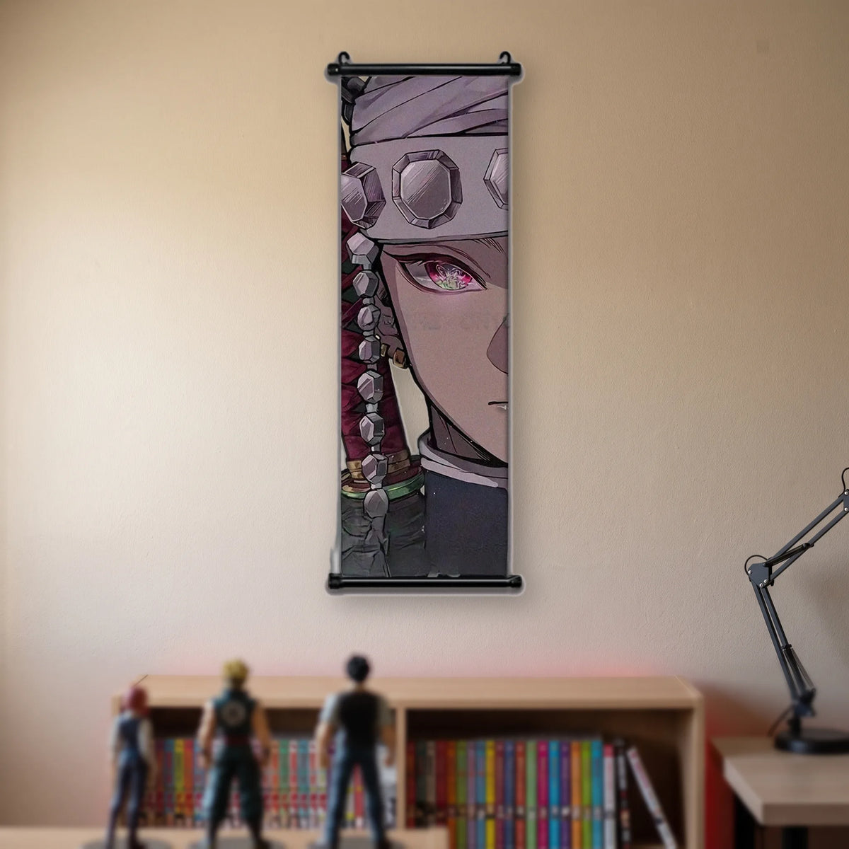 Kakémono Demon Slayer Tengen Uzui en gros plan, bandeau à pierres et œil rose, suspendu au mur beige d'une chambre au-dessus d'une étagère de tomes de manga