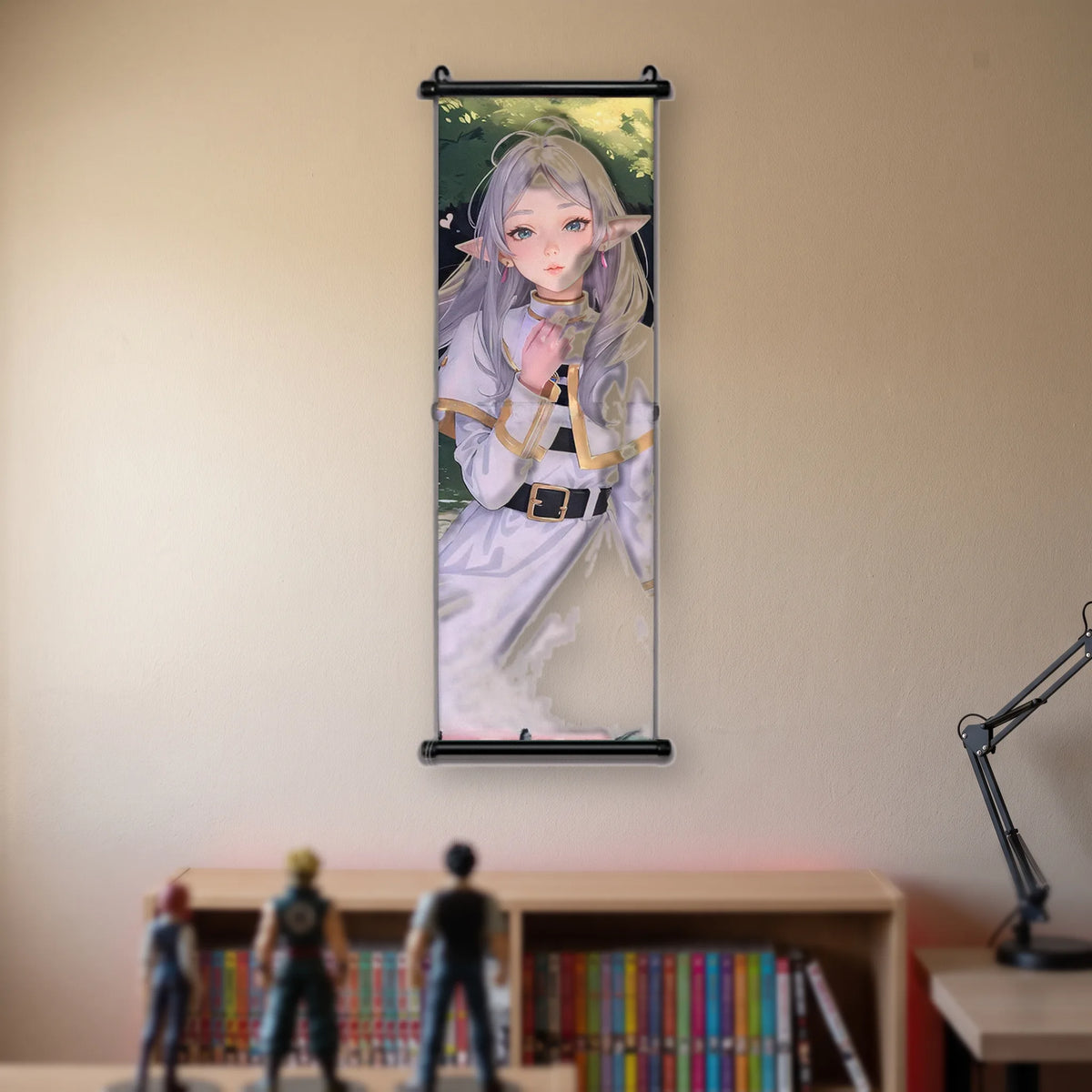 Kakémono Frieren, Frieren la main levée près du visage, devant un feuillage vert, suspendu au mur beige d'une chambre au-dessus d'une étagère de tomes de manga
