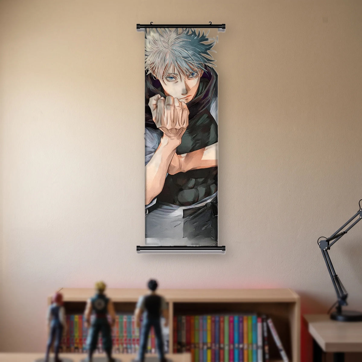 Kakémono Jujutsu Kaisen Satoru Gojo, les deux poings joints devant le visage, suspendu au mur beige d'une chambre au-dessus d'une étagère de tomes de manga et de figurines