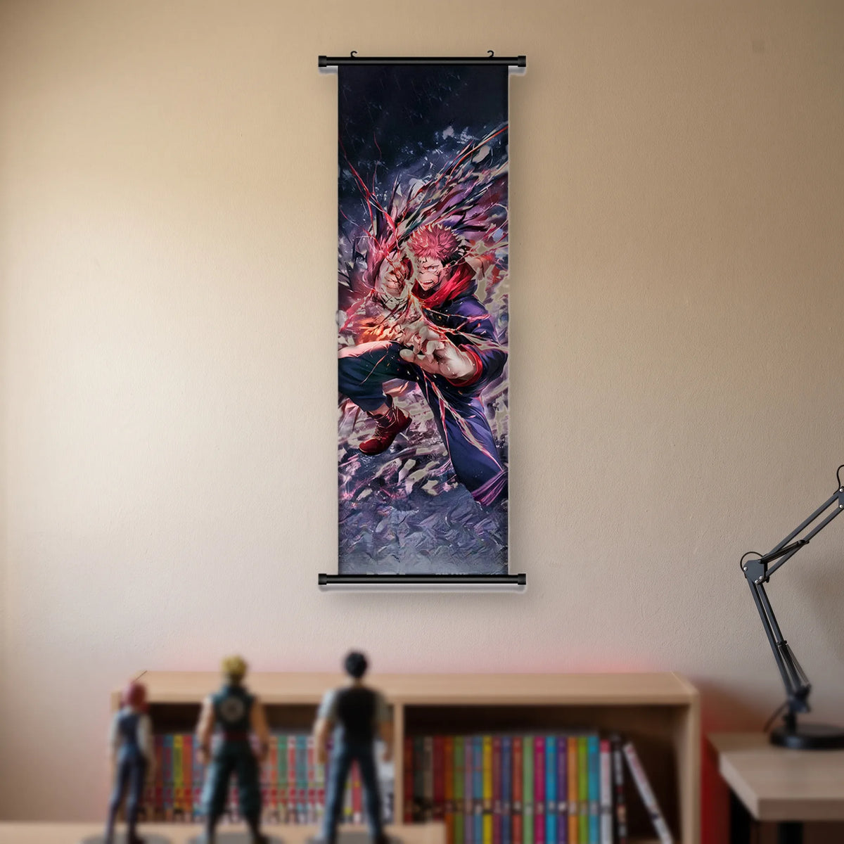 Kakémono Jujutsu Kaisen Sukuna accroupi sur des gravats, entouré de fils rouges, suspendu au mur beige d'une chambre au-dessus d'une étagère de tomes de manga et de figurines